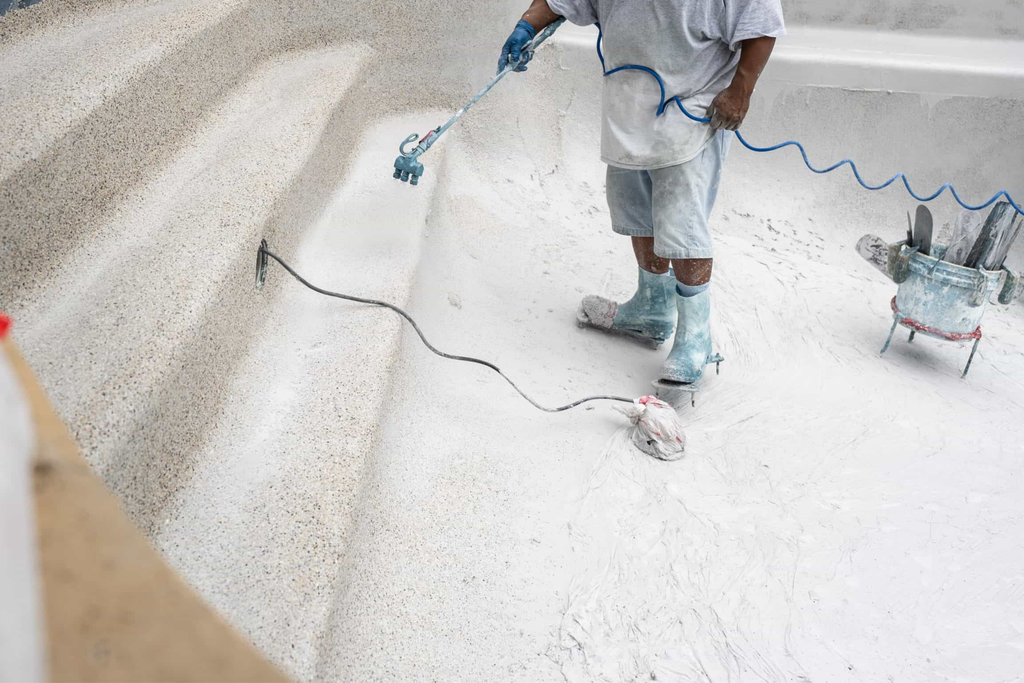 Pool technician applying new plaster finish to the interior of a South Florida pool during resurfacing.